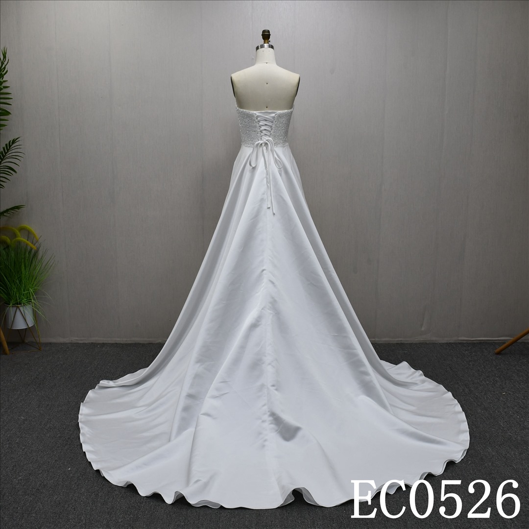 An ivory A-line wedding dress with lace and sequins on the chest and lace up back