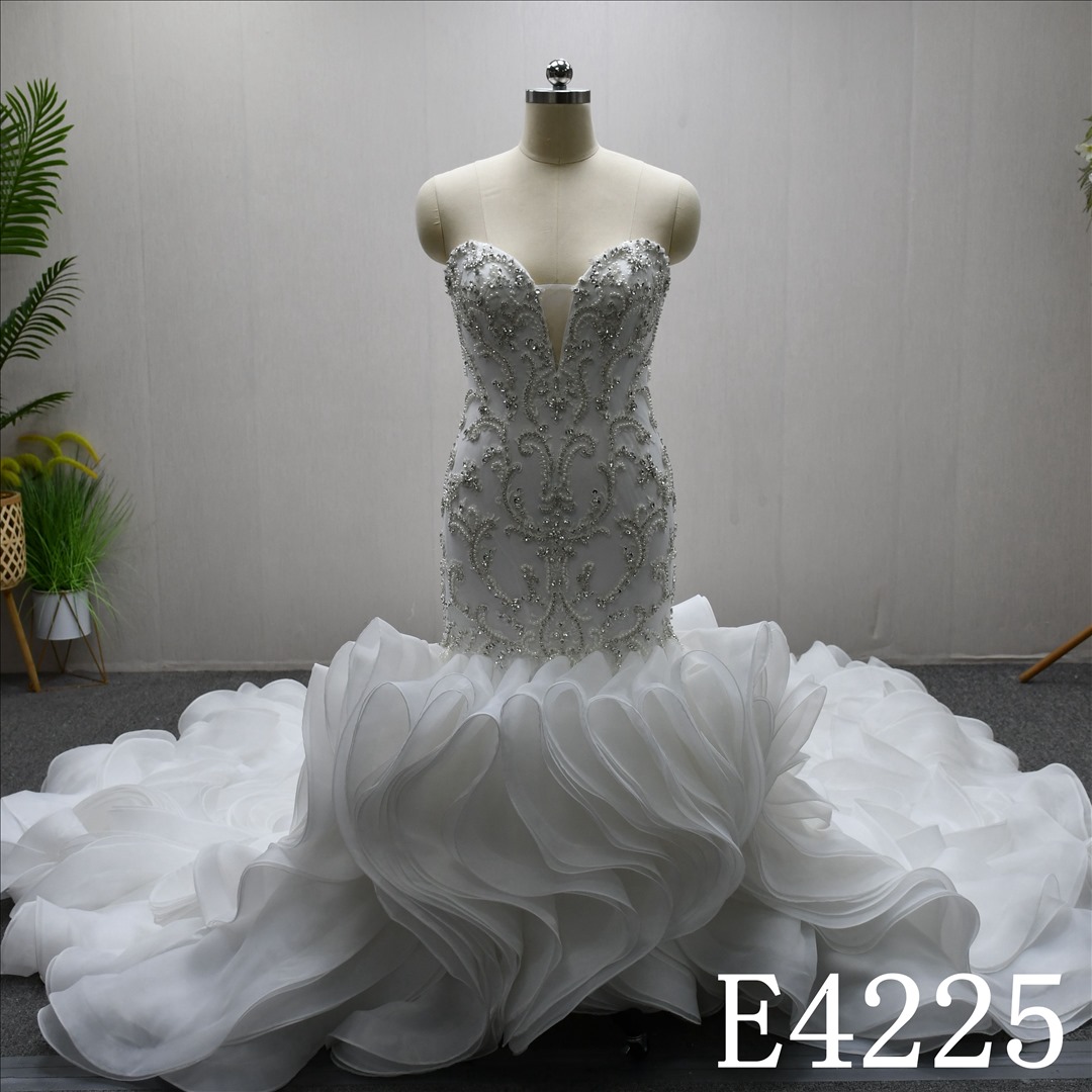 A luxurious mermaid wedding evening gown with a lace and rhinestones and ruffled hem