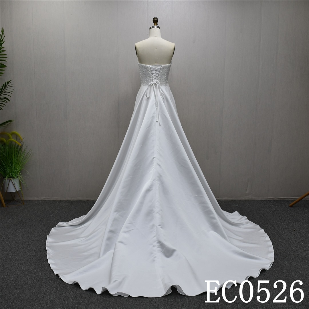 An ivory A-line wedding dress with lace and sequins on the chest and lace up back