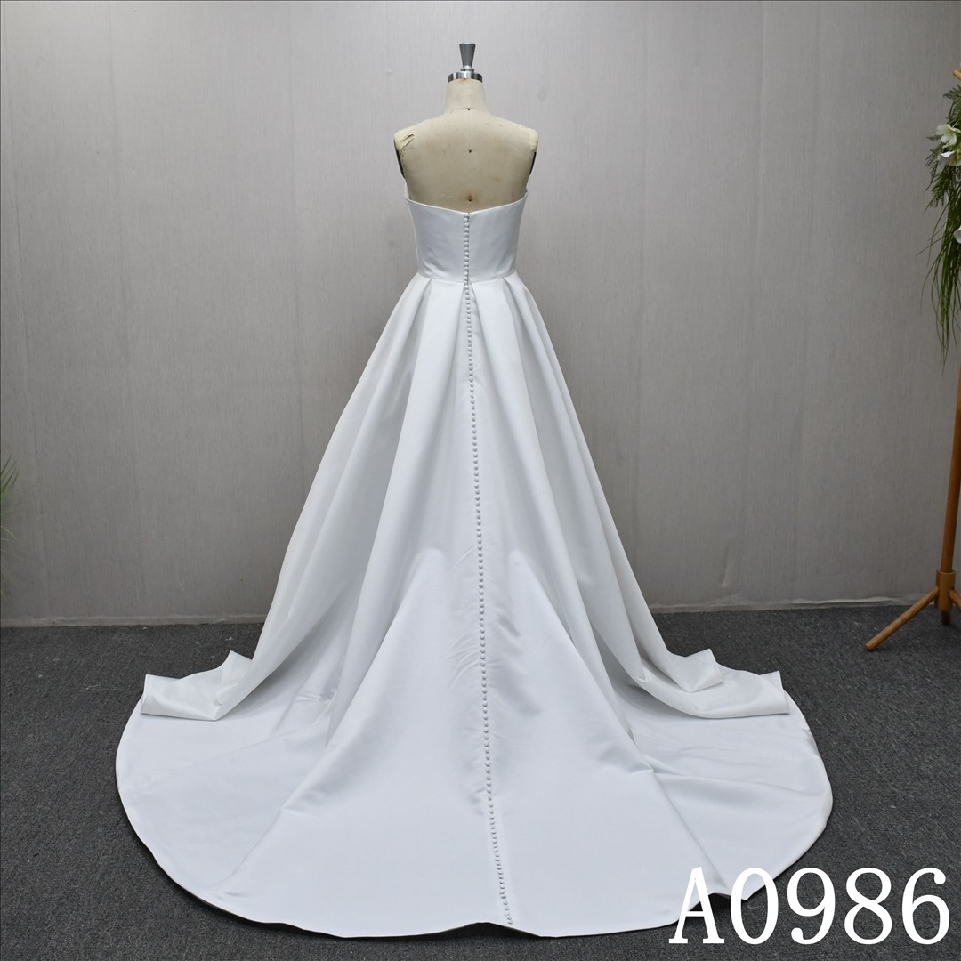 An A-line ivory wedding dress with a simple yet unique design and back zipper and button.