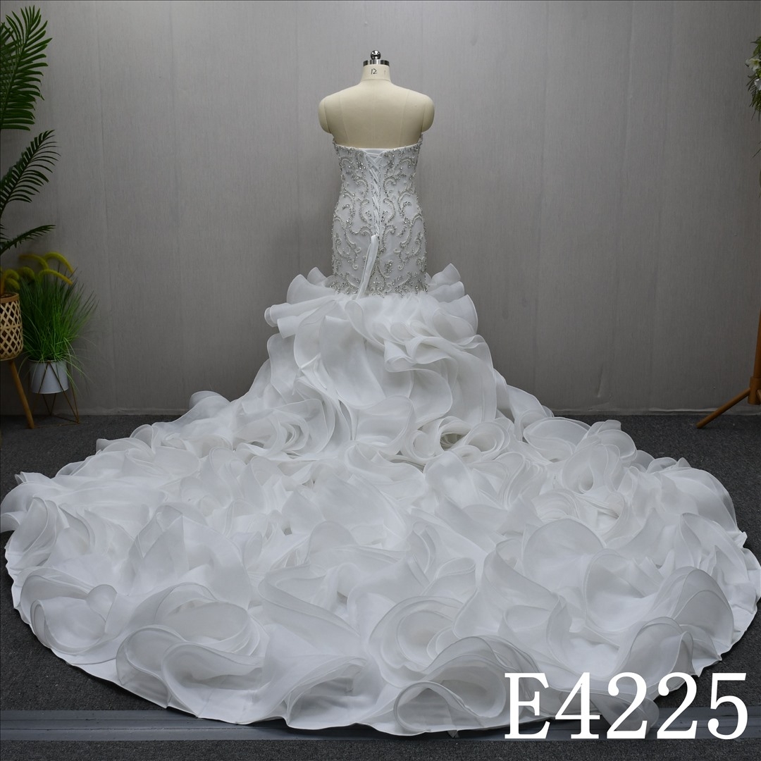 A luxurious mermaid wedding evening gown with a lace and rhinestones and ruffled hem